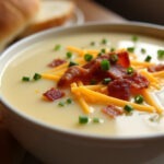 Creamy potato soup topped with bacon, cheese, and chives, a comforting meal.