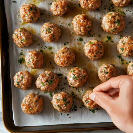 Forming meatballs and placing them on a baking sheet.