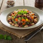 Delicious dense bean salad beautifully garnished and served in a bowl, highlighting fresh vegetables and vibrant colors.