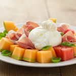 Finished Melon-Burrata-Prosciutto Salad ready to be served, showcasing bright colors and fresh ingredients.