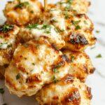 Colorful grilled chicken skewers lined up on a rustic wooden platter, glazed with a golden garlic ranch marinade, garnished with fresh herbs and lemon wedges, with char marks visible on the succulent chicken pieces and vibrant vegetables interspersed.